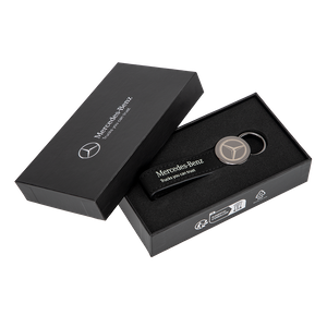 Mercedes-Benz-Schlüsselanhänger mit Lederschlaufe und Logo, präsentiert in einer stilvollen schwarzen Geschenkbox mit Logo-Aufdruck. 3