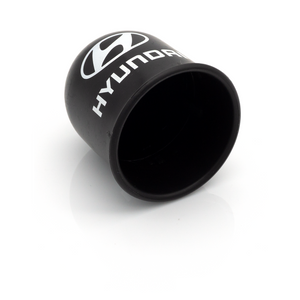 Schwarze Kunststoffkappe mit Hyundai-Logo, seitlich liegend und teilweise innen sichtbar 1