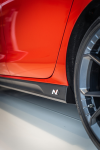 Seitliche Ansicht eines roten Autos mit einem montierten N-Logo auf der schwarzen Seitenverkleidung 4