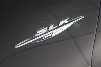 Nahaufnahme des Schriftzugs ‚SLK 2LOOK Edition‘ auf der Karosserie eines schwarzen Autos.