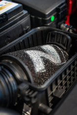 Nahaufnahme eines eingebauten Luftfilters mit N-Logo im Motorraum eines Autos.